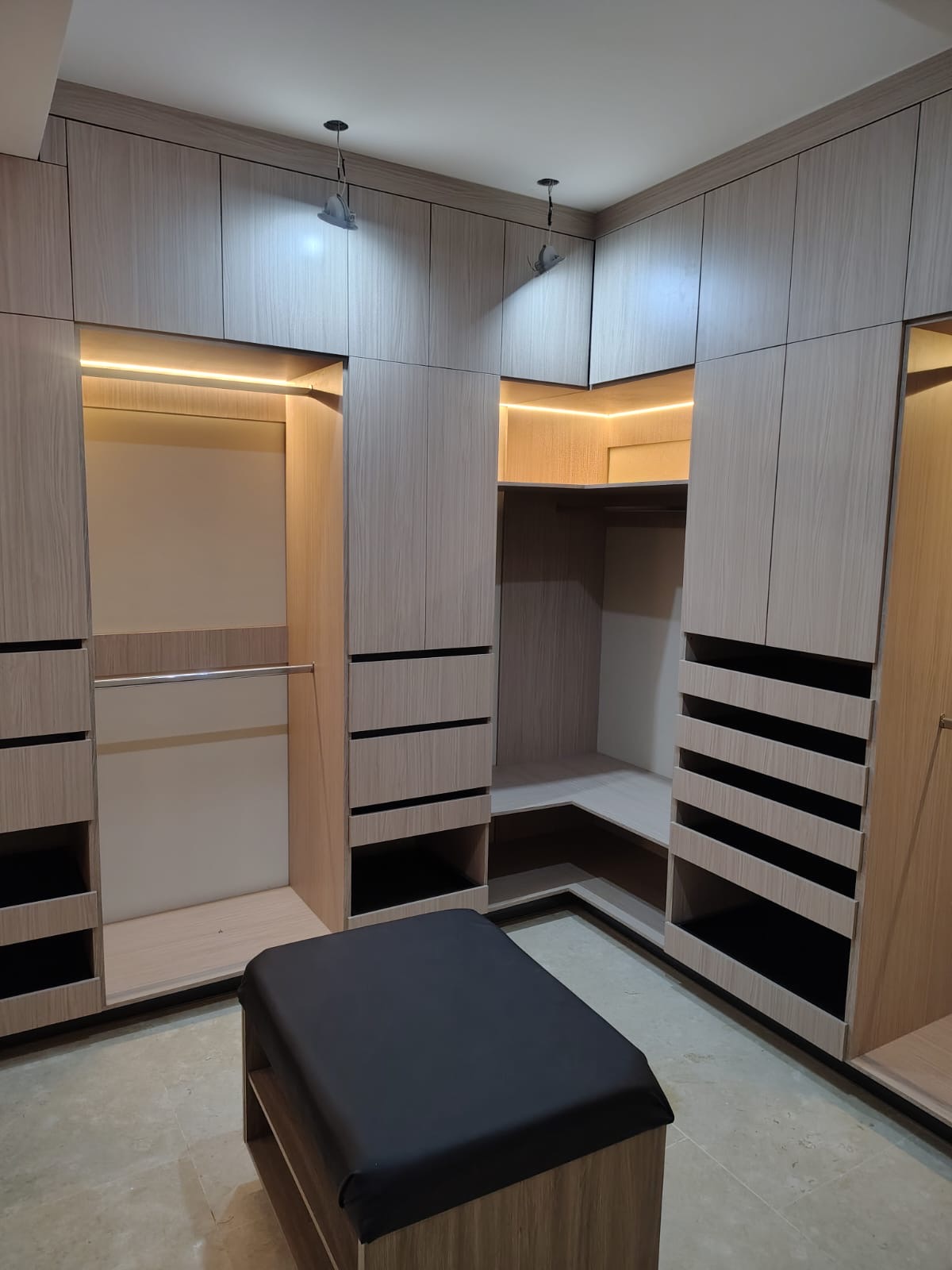 Vestidor walk-in a la medida con iluminación LED, cajoneras, zapateras y taburete central