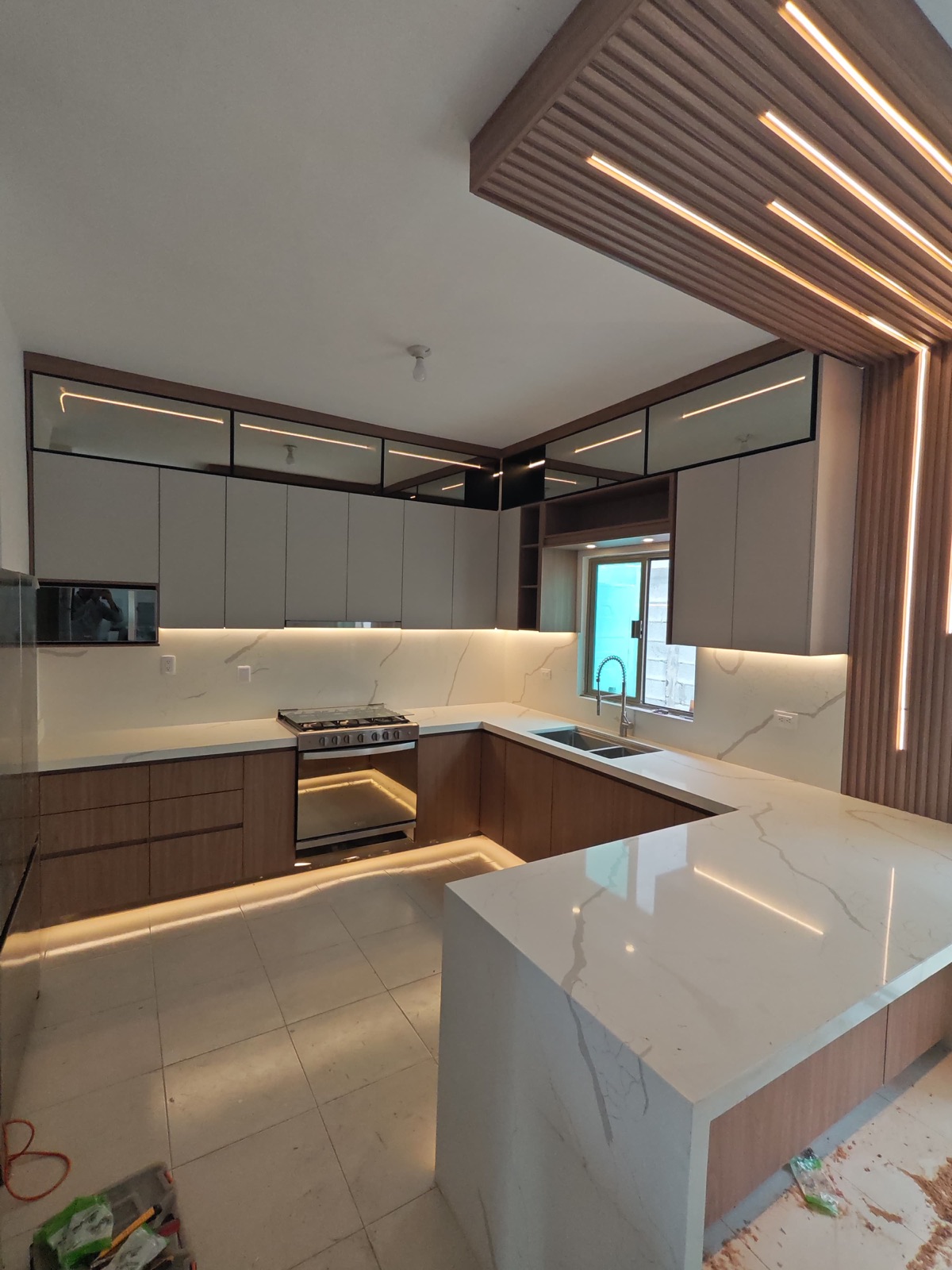 Cocina con muro de celosía de madera, mármol veteado y luz bajo gabinetes