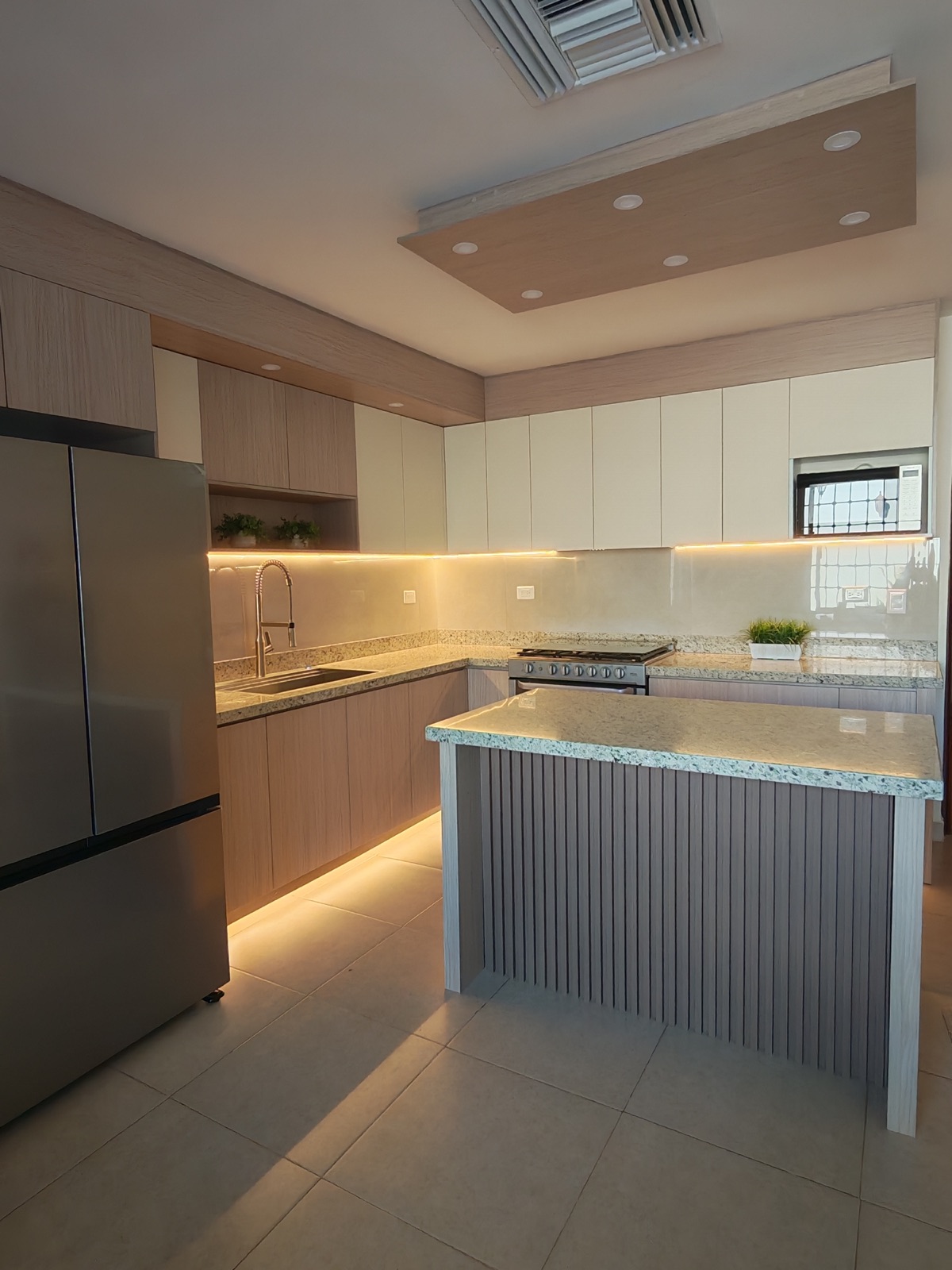 Cocina con isla de base de celosía, cubierta de granito y plafón de madera con luces empotradas